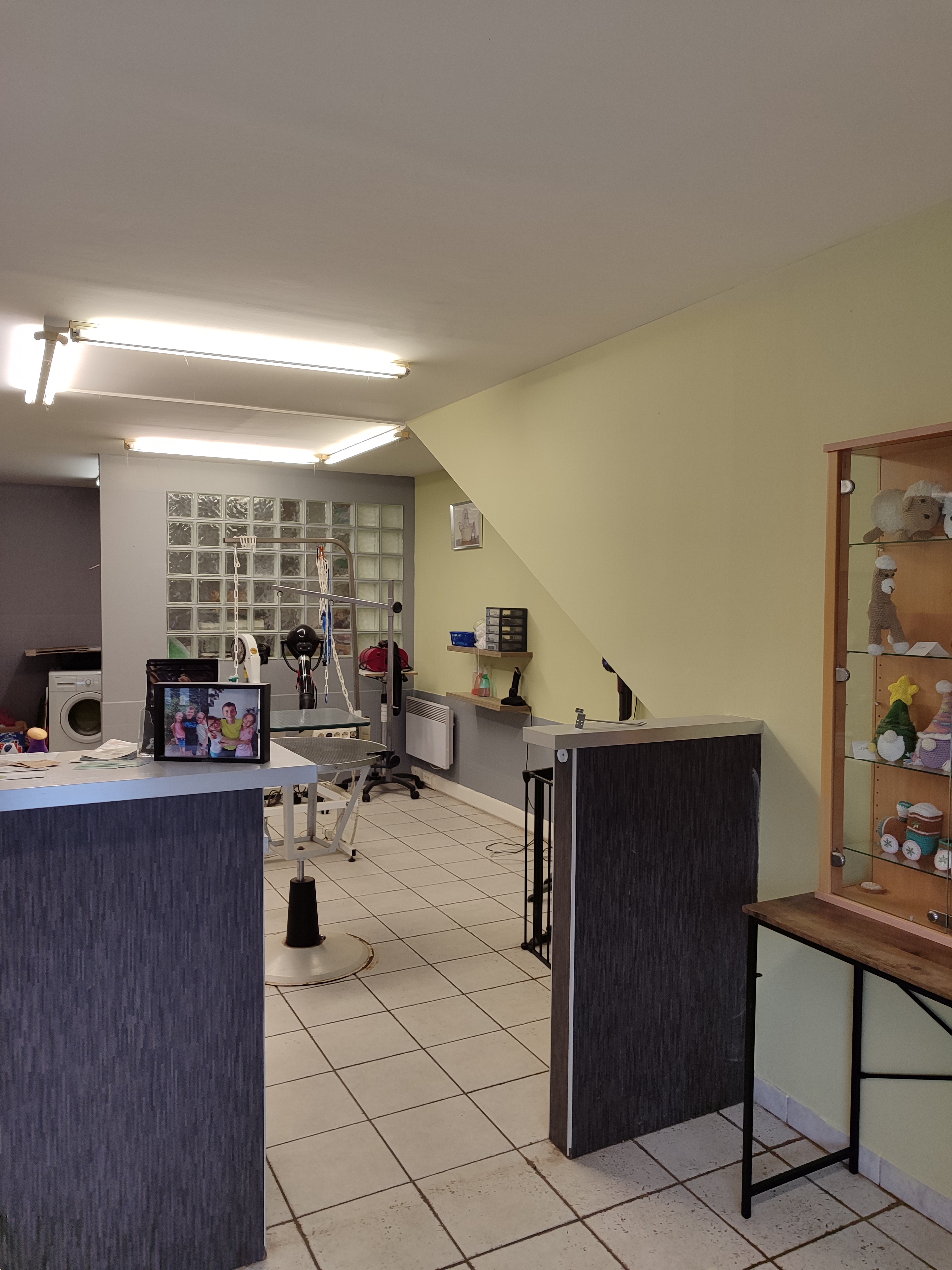 Détail accueil et murs : tons clairs, comptoir anthracite, espace d’attente côté client